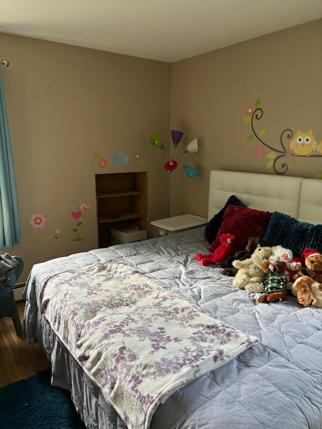 bedroom featuring hardwood / wood-style flooring and a baseboard heating unit