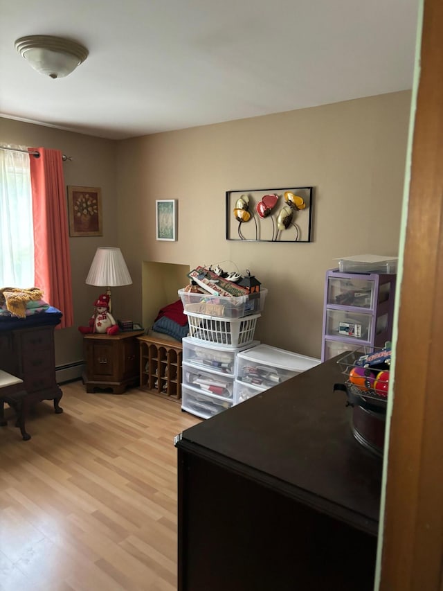 bedroom featuring a baseboard heating unit and light wood-type flooring