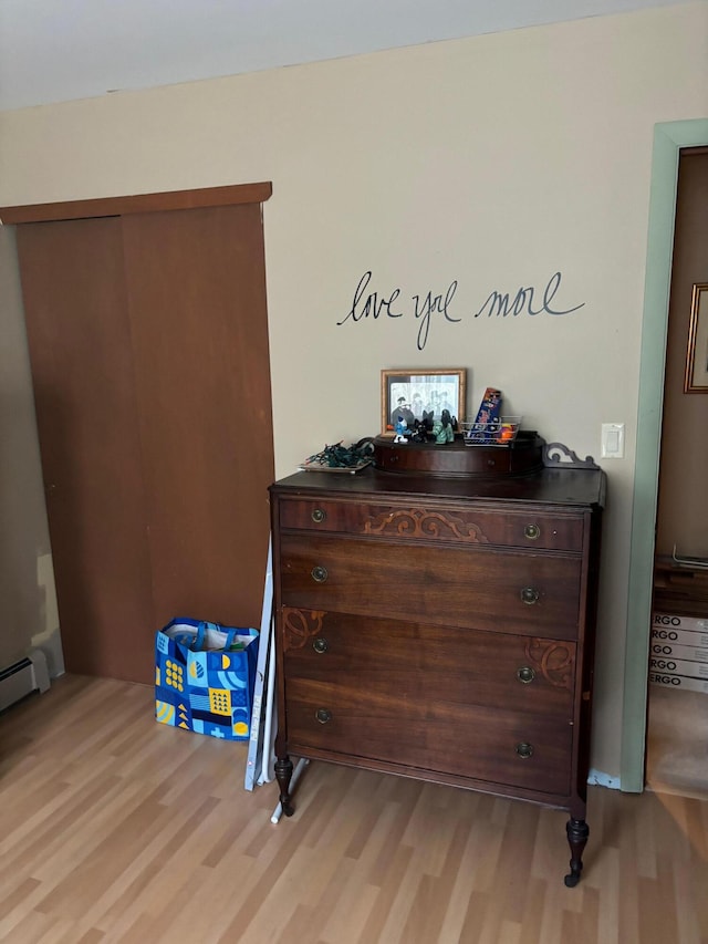 bedroom featuring light hardwood / wood-style floors and a baseboard heating unit