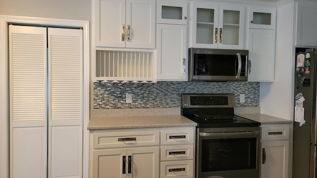 kitchen featuring tasteful backsplash, light stone countertops, stainless steel appliances, and white cabinets