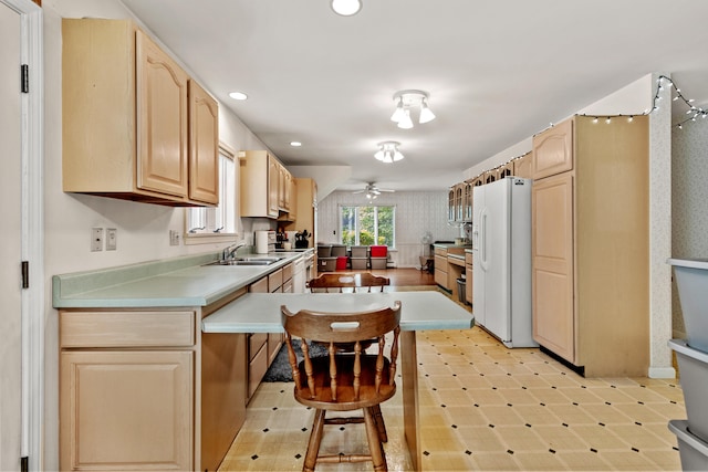 kitchen featuring white refrigerator with ice dispenser, a breakfast bar, sink, light brown cabinets, and ceiling fan