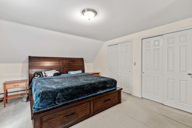 bedroom with multiple closets, light carpet, and lofted ceiling