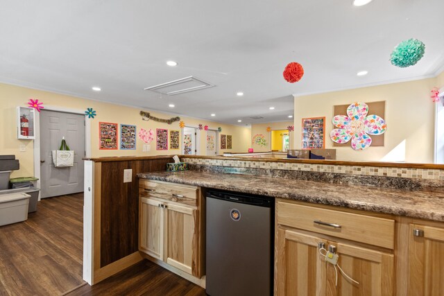 kitchen with dark stone countertops, ornamental molding, dark hardwood / wood-style flooring, kitchen peninsula, and stainless steel dishwasher