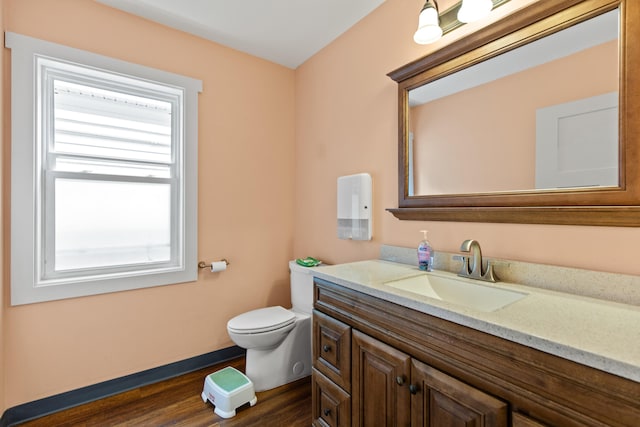 bathroom featuring a wealth of natural light, vanity, toilet, and hardwood / wood-style floors