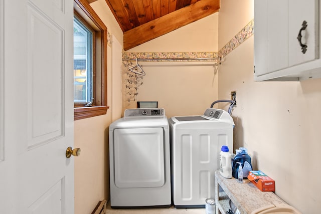 laundry area featuring wood ceiling, washing machine and clothes dryer, and cabinets