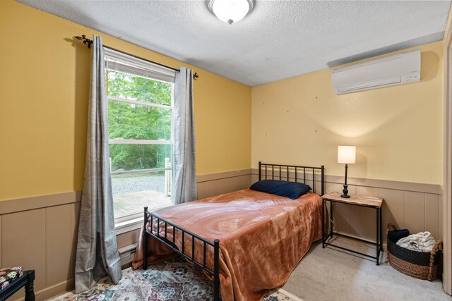 carpeted bedroom featuring a textured ceiling and a wall mounted air conditioner