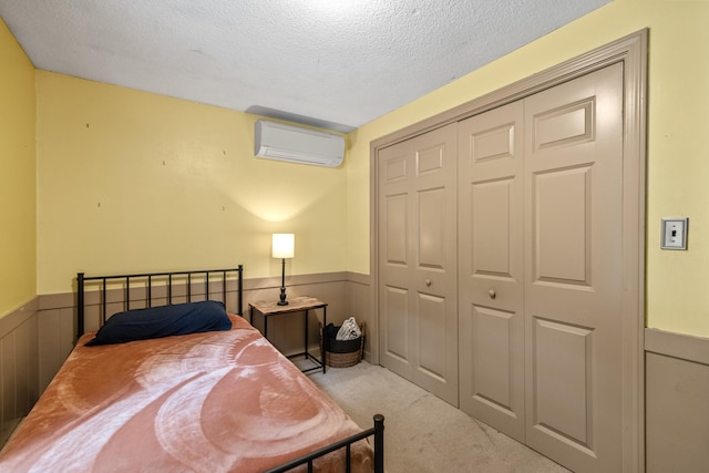 carpeted bedroom featuring a textured ceiling, wood walls, a wall mounted air conditioner, and a closet