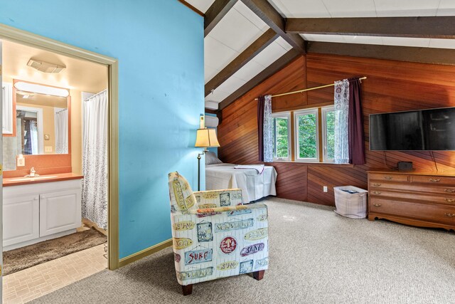 sitting room featuring lofted ceiling with beams, sink, wood walls, and light colored carpet