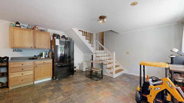 kitchen with black fridge, light brown cabinetry, and crown molding