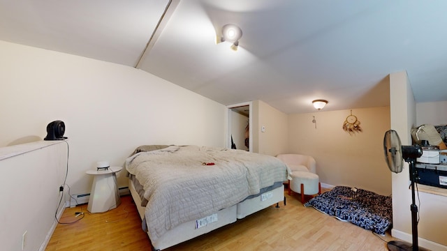 bedroom featuring a baseboard radiator, light hardwood / wood-style floors, and lofted ceiling