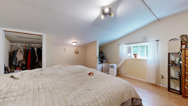 bedroom featuring vaulted ceiling, light hardwood / wood-style flooring, and a closet