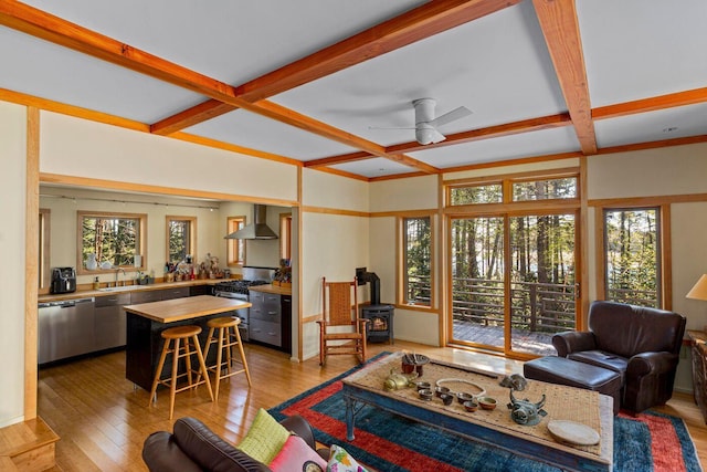 living room with ceiling fan, sink, beamed ceiling, coffered ceiling, and light wood-type flooring