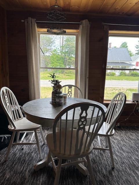 dining area with wooden ceiling, wooden walls, and a healthy amount of sunlight