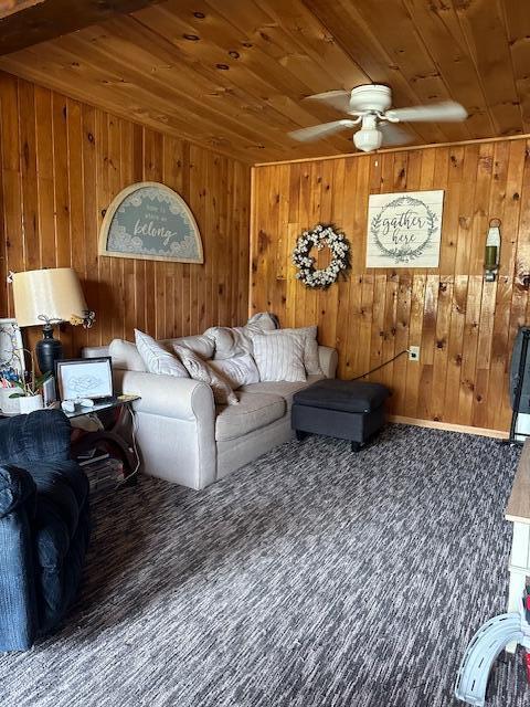 living room featuring ceiling fan, wood walls, and wooden ceiling