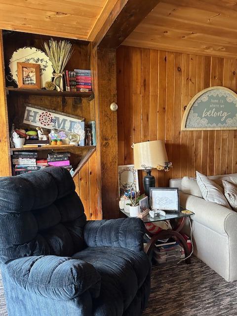 living room featuring beam ceiling, wooden walls, and wood ceiling