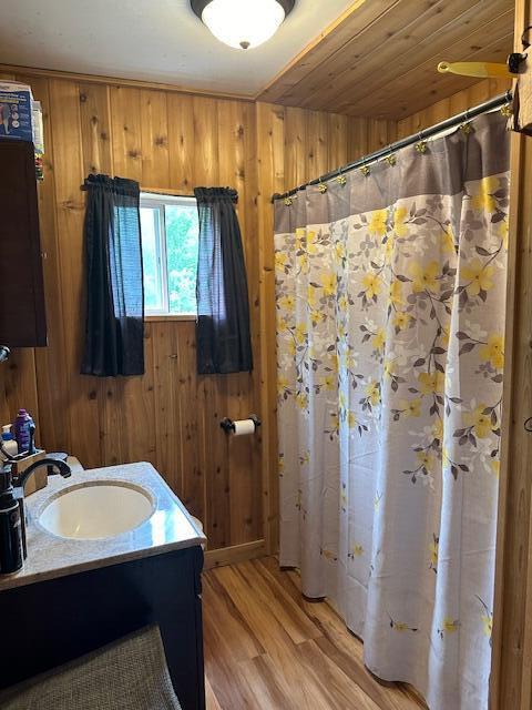 bathroom with vanity, hardwood / wood-style flooring, wood ceiling, and wood walls