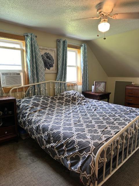 carpeted bedroom featuring a textured ceiling, cooling unit, ceiling fan, and lofted ceiling