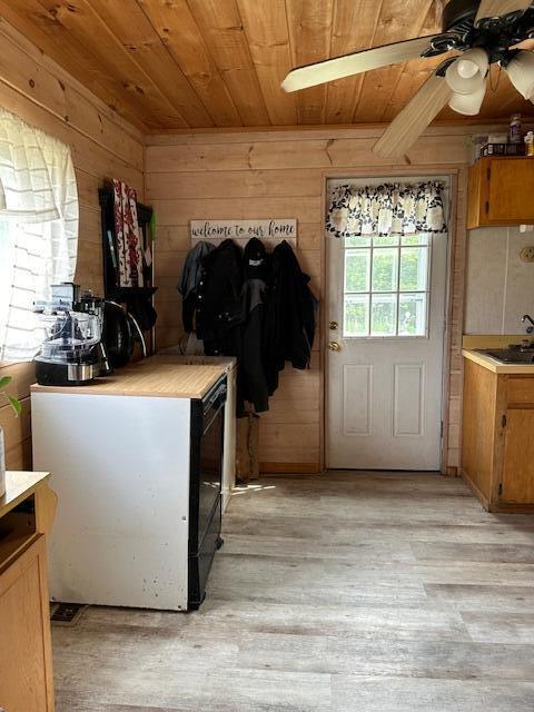 kitchen featuring ceiling fan, wood walls, light wood-type flooring, and wooden ceiling