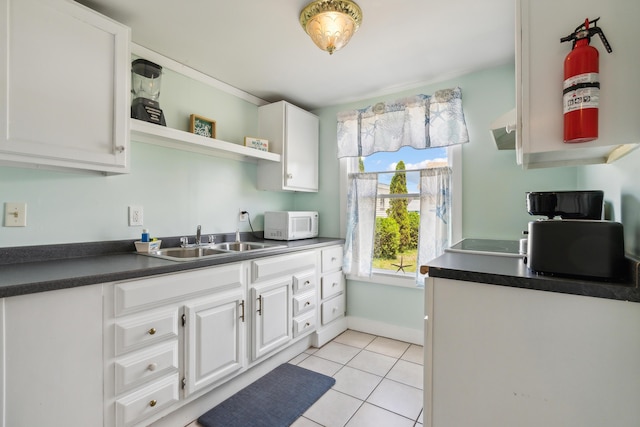 kitchen featuring light tile patterned flooring, white cabinetry, and sink