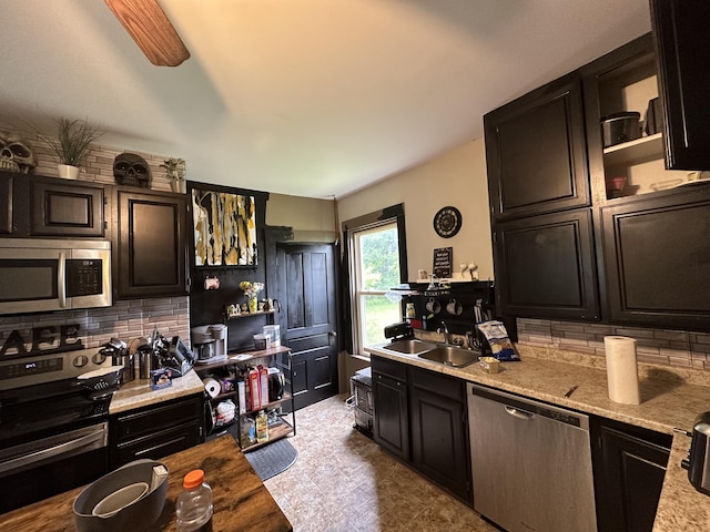 kitchen featuring sink, appliances with stainless steel finishes, tasteful backsplash, light stone counters, and dark brown cabinetry