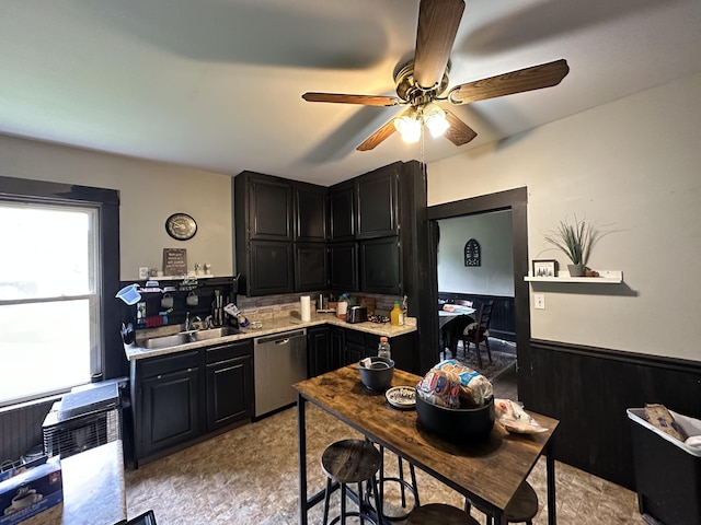 kitchen with stainless steel dishwasher, wooden walls, and sink