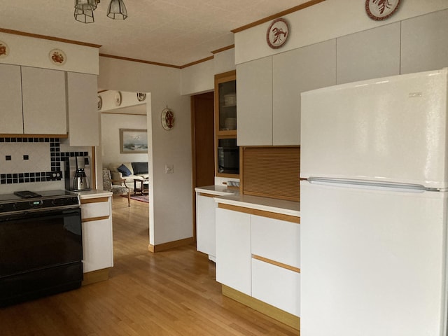 kitchen featuring backsplash, electric range, crown molding, light wood-type flooring, and white refrigerator