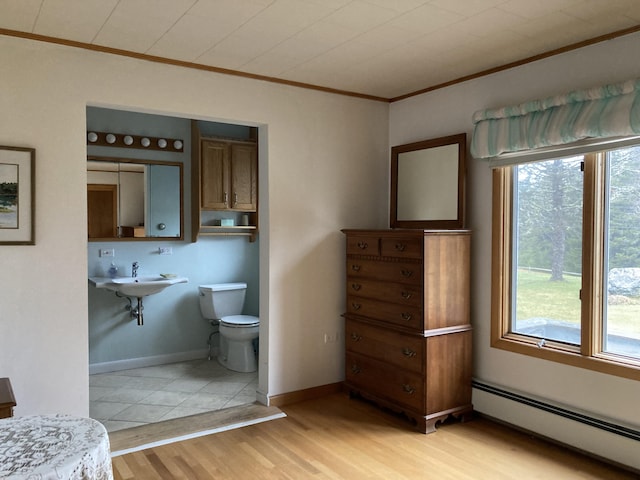 bathroom featuring hardwood / wood-style flooring, a baseboard heating unit, crown molding, and toilet