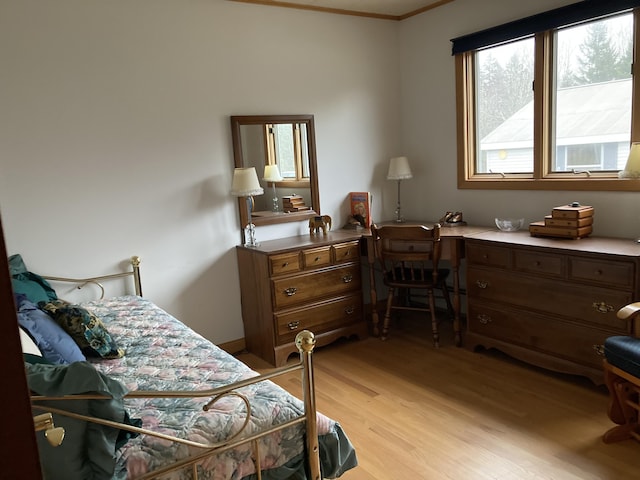 bedroom featuring ornamental molding, built in desk, and light wood-type flooring