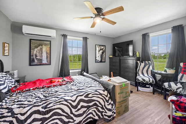 bedroom with an AC wall unit, ceiling fan, and light hardwood / wood-style flooring