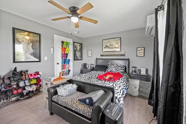 bedroom featuring a wall mounted air conditioner, light hardwood / wood-style floors, and ceiling fan