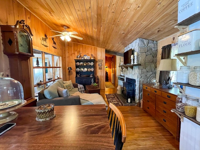 dining space with wood ceiling, wooden walls, ceiling fan, lofted ceiling, and light hardwood / wood-style flooring