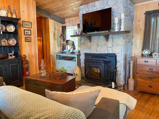 living room featuring wooden ceiling, a wood stove, wood-type flooring, and wooden walls