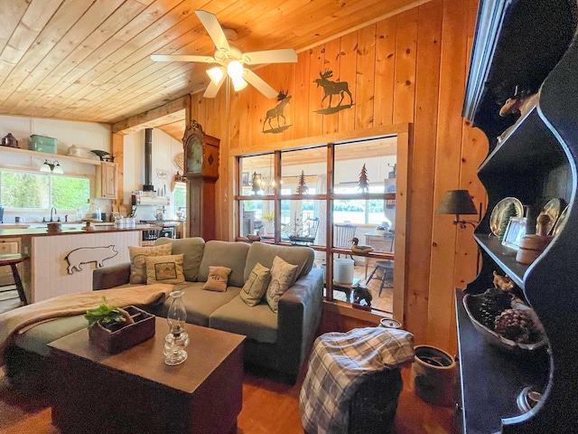 living room featuring ceiling fan, vaulted ceiling, sink, wooden walls, and wood ceiling