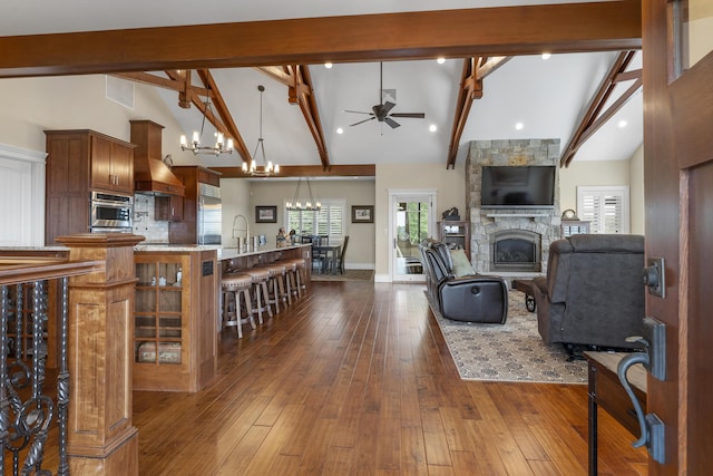 living room featuring a stone fireplace, beam ceiling, dark hardwood / wood-style floors, high vaulted ceiling, and ceiling fan with notable chandelier