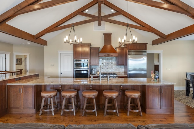 kitchen with custom exhaust hood, backsplash, stainless steel appliances, and pendant lighting