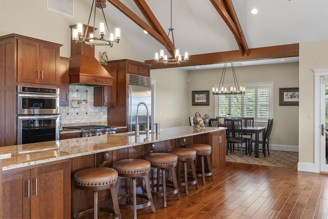 kitchen featuring decorative light fixtures, stainless steel appliances, tasteful backsplash, and beamed ceiling