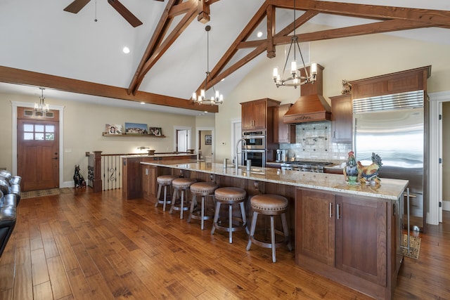 kitchen featuring beam ceiling, decorative backsplash, a large island with sink, and pendant lighting