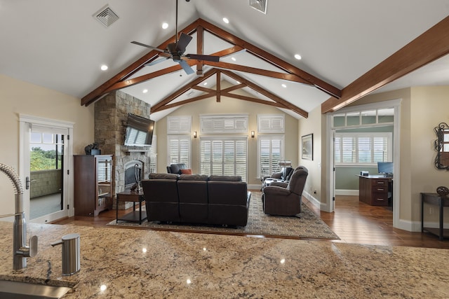 living room featuring hardwood / wood-style floors, ceiling fan, a fireplace, vaulted ceiling with beams, and sink