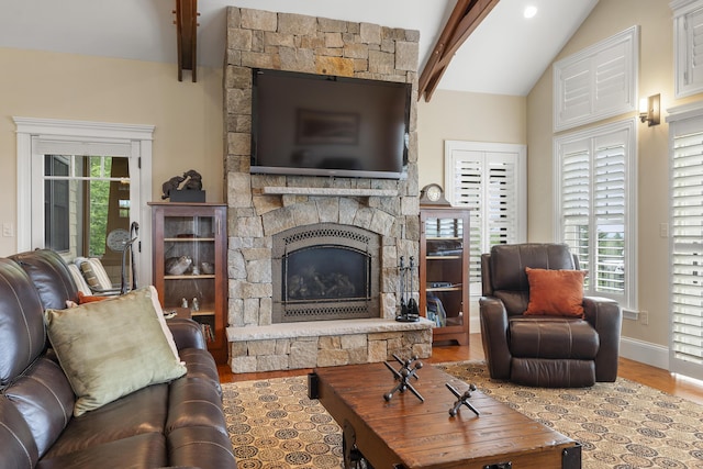 living room with hardwood / wood-style floors, a stone fireplace, and lofted ceiling with beams