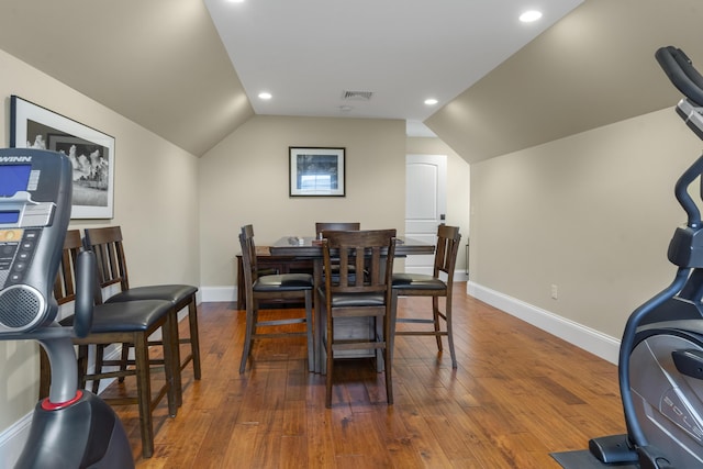 dining room with dark wood-type flooring and vaulted ceiling