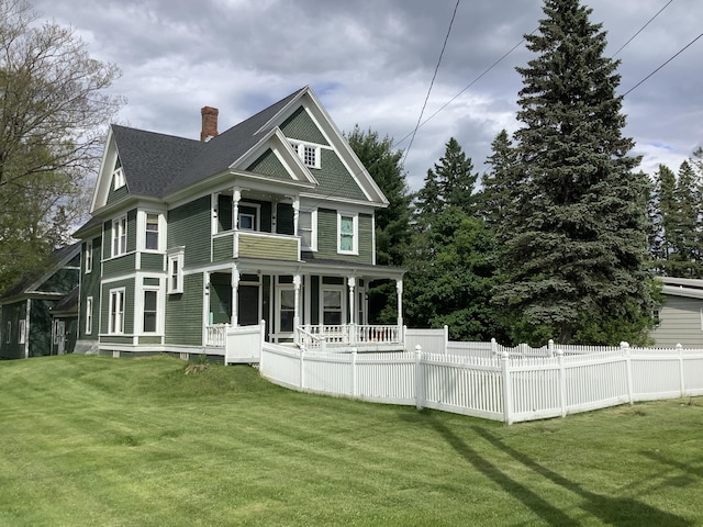 back of house featuring covered porch and a yard