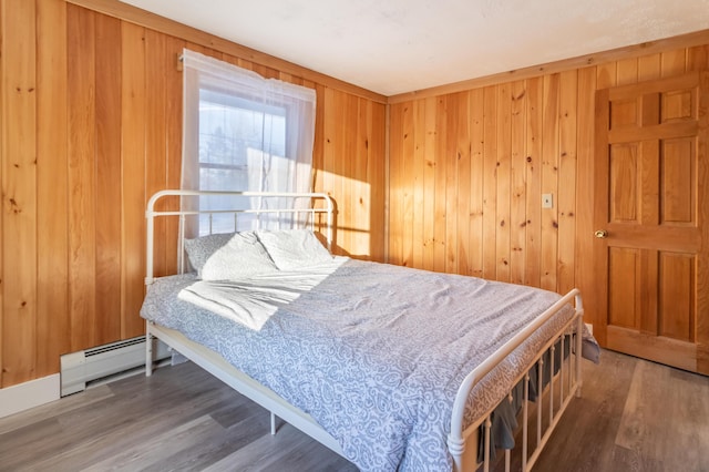 bedroom featuring hardwood / wood-style floors, wooden walls, and baseboard heating