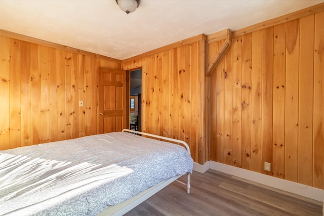 bedroom with wooden walls, wood finished floors, and baseboards