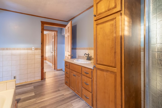 full bathroom featuring vanity, tile walls, crown molding, and wood finished floors