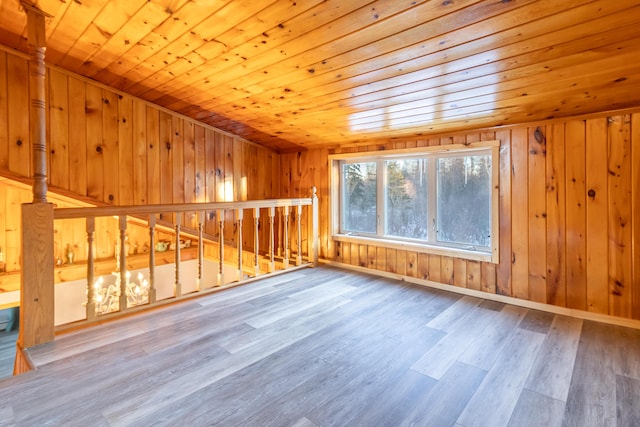 additional living space featuring wooden ceiling, wooden walls, wood finished floors, and baseboards