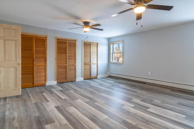 unfurnished bedroom featuring multiple closets, ceiling fan, light hardwood / wood-style flooring, and a baseboard heating unit