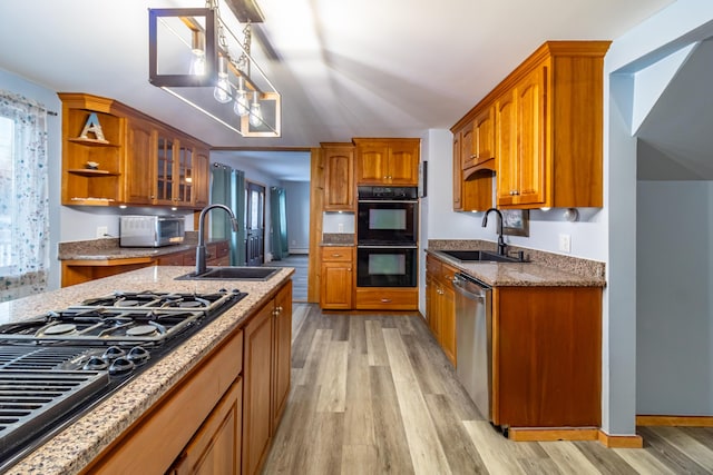 kitchen with decorative light fixtures, light hardwood / wood-style floors, sink, and black appliances