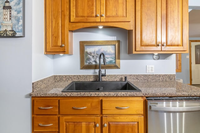 kitchen with dishwasher, brown cabinets, stone counters, and a sink