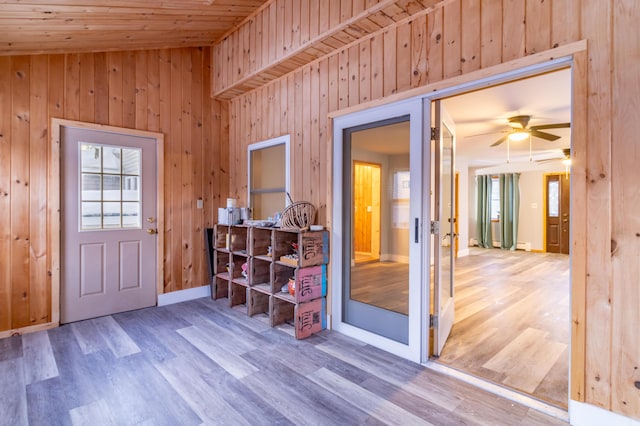 interior space featuring wood-type flooring, ceiling fan, wood ceiling, and wooden walls