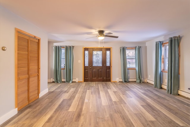 entrance foyer with ceiling fan, a baseboard heating unit, and light wood-type flooring